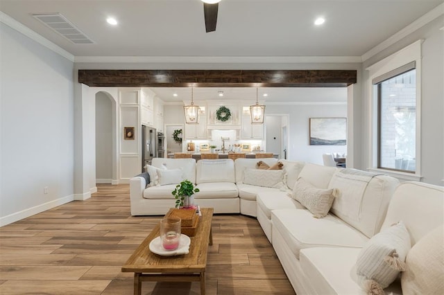 living area featuring visible vents, arched walkways, ornamental molding, light wood-style floors, and recessed lighting