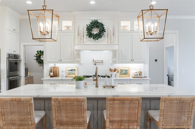 kitchen featuring double oven, crown molding, backsplash, and a notable chandelier