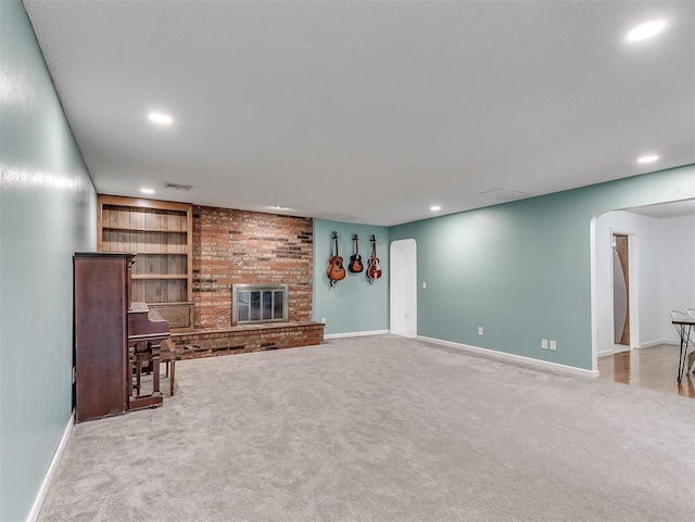 unfurnished living room with a brick fireplace, carpet, and built in shelves