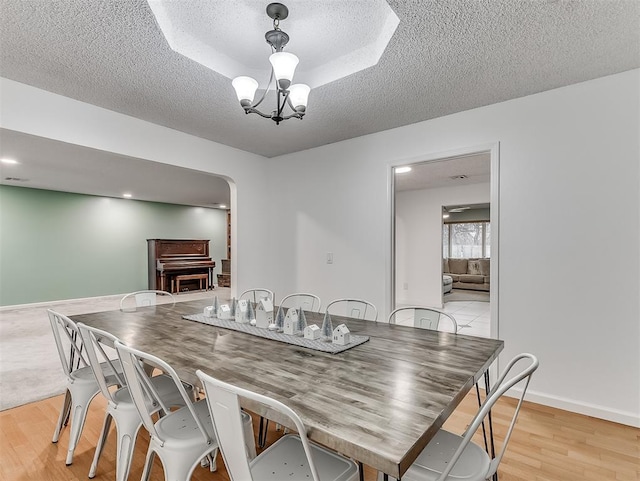 dining space with a notable chandelier, light hardwood / wood-style flooring, and a textured ceiling