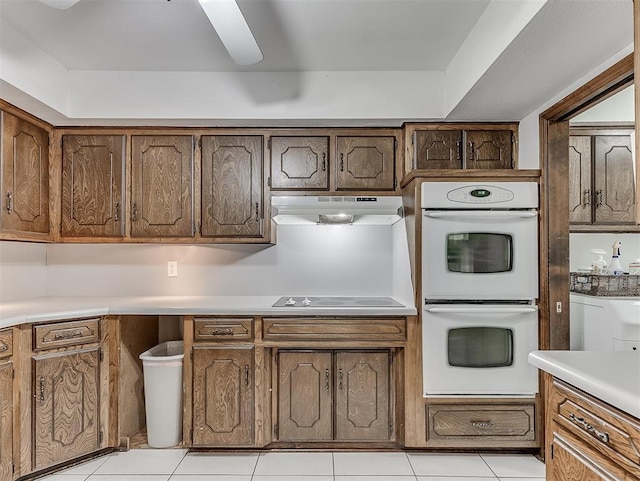 kitchen featuring black electric cooktop, double oven, and light tile patterned floors