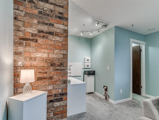 interior space featuring rail lighting, light carpet, and a textured ceiling