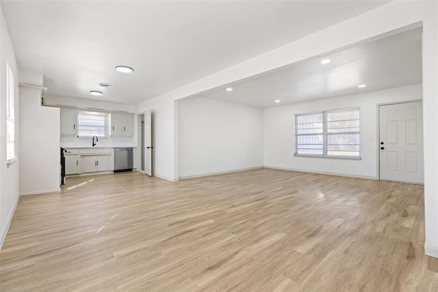 unfurnished living room featuring sink and light hardwood / wood-style floors