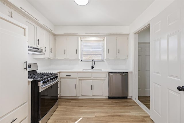 kitchen featuring sink, light hardwood / wood-style flooring, appliances with stainless steel finishes, white cabinetry, and tasteful backsplash