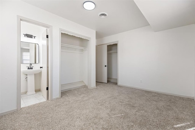 unfurnished bedroom with light colored carpet and connected bathroom