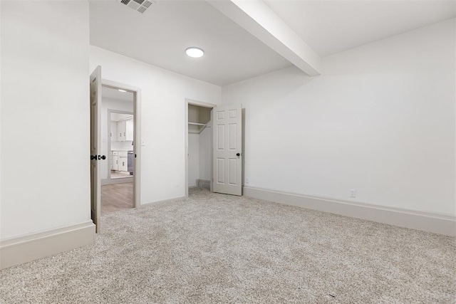 unfurnished bedroom with beamed ceiling, carpet flooring, and a closet