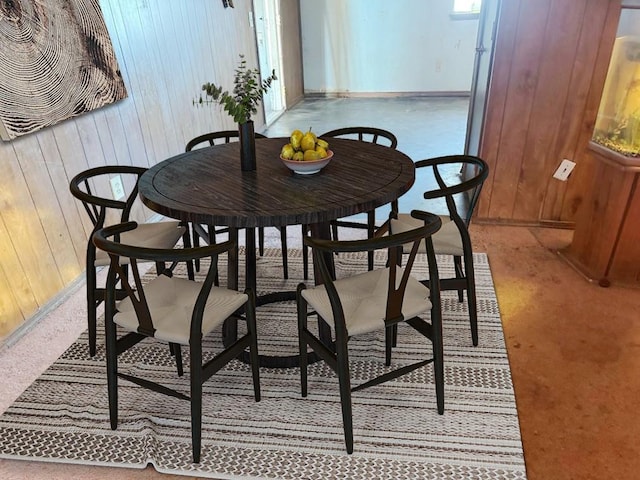 dining room with light colored carpet and wood walls