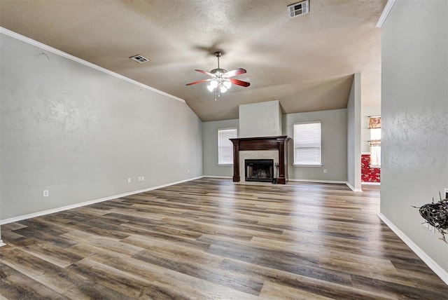 unfurnished living room with lofted ceiling, crown molding, dark hardwood / wood-style floors, ceiling fan, and a tiled fireplace