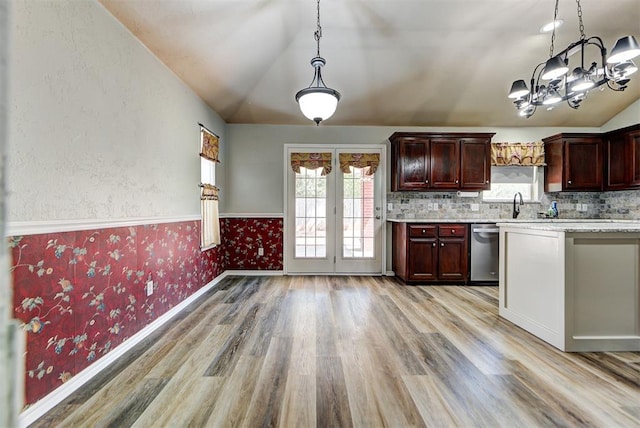 kitchen with lofted ceiling, decorative light fixtures, dishwasher, and light wood-type flooring