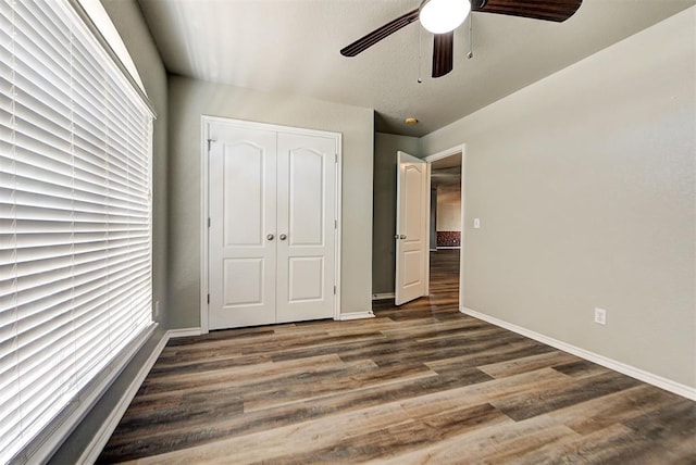 unfurnished bedroom featuring ceiling fan, dark hardwood / wood-style floors, and a closet