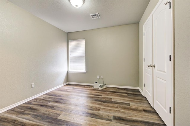 unfurnished bedroom with dark wood-type flooring, a closet, and a textured ceiling