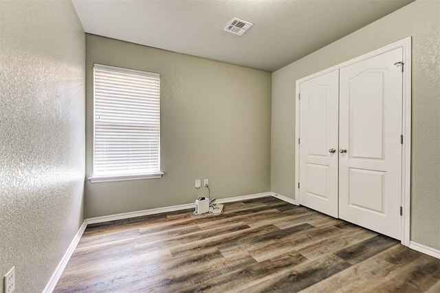 unfurnished bedroom featuring a closet and dark hardwood / wood-style floors