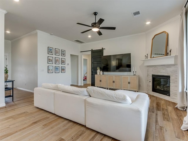 living room featuring ornamental molding, a barn door, and light wood-type flooring