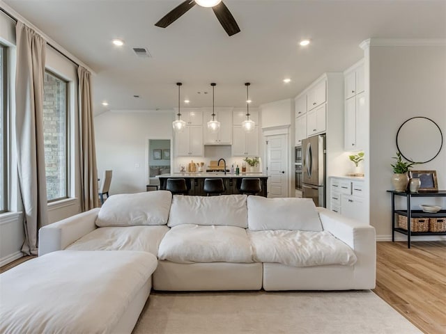 living room featuring sink, ceiling fan, and light wood-type flooring