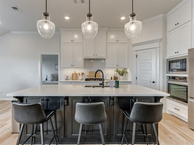 kitchen featuring a large island with sink, white cabinetry, and stainless steel oven