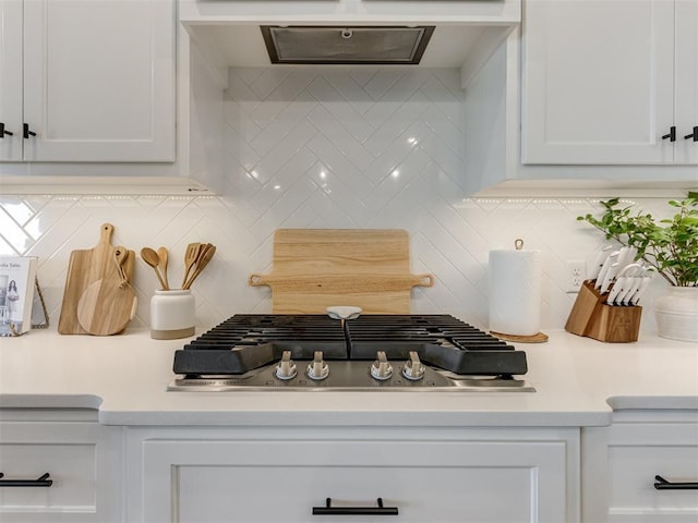 interior space featuring stainless steel gas stovetop, white cabinetry, and backsplash