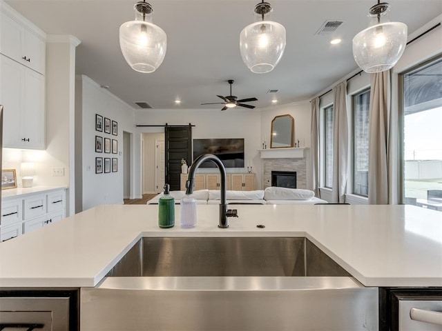 kitchen with white cabinetry, sink, a barn door, and a kitchen island with sink