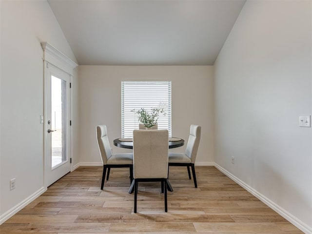 dining room with vaulted ceiling and light wood-type flooring