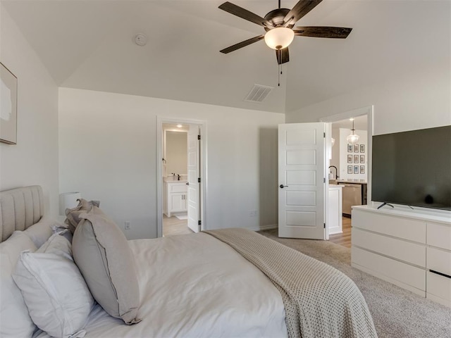 bedroom with light carpet, connected bathroom, vaulted ceiling, and sink