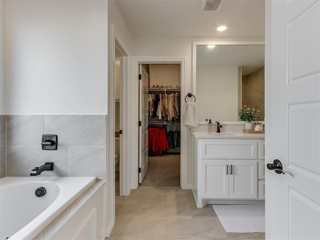 bathroom featuring vanity, a washtub, tile walls, and toilet