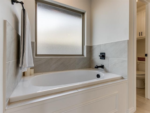 bathroom with hardwood / wood-style flooring, toilet, and a bathing tub