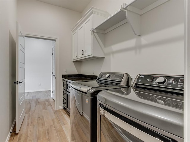 laundry area featuring cabinets, washer and dryer, and light hardwood / wood-style floors