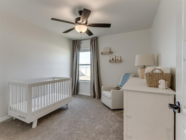 carpeted bedroom featuring a crib and ceiling fan