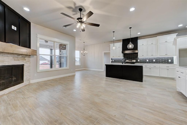 kitchen featuring white cabinetry, hanging light fixtures, and a center island with sink