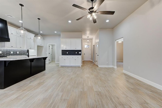 kitchen with a breakfast bar area, decorative light fixtures, light hardwood / wood-style floors, decorative backsplash, and white cabinets