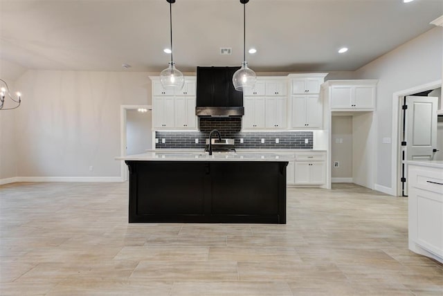 kitchen featuring sink, an island with sink, hanging light fixtures, and white cabinets