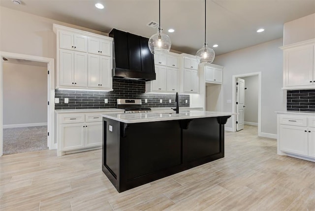 kitchen featuring sink, hanging light fixtures, electric range, an island with sink, and white cabinets