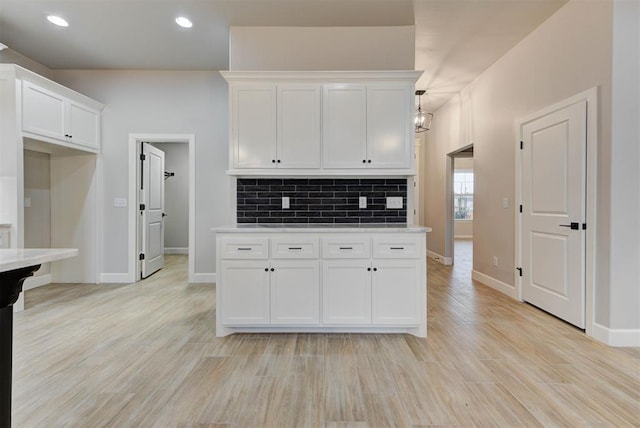 kitchen with white cabinetry, backsplash, and light hardwood / wood-style flooring