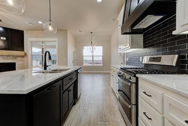 kitchen with stainless steel appliances, white cabinetry, sink, and a kitchen island with sink