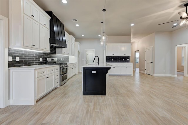 kitchen with pendant lighting, a kitchen island with sink, double oven range, custom range hood, and white cabinets