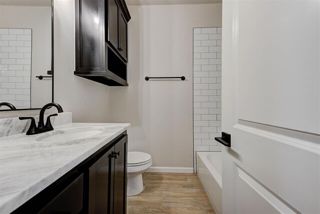 full bathroom with vanity, tiled shower / bath combo, wood-type flooring, and toilet