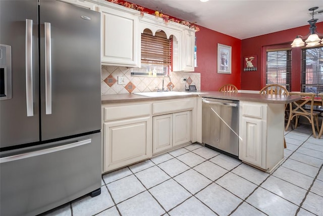 kitchen with appliances with stainless steel finishes, pendant lighting, sink, decorative backsplash, and kitchen peninsula