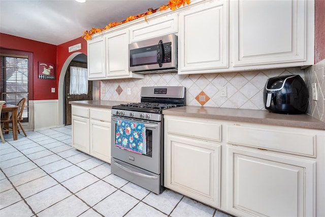 kitchen featuring white cabinetry, appliances with stainless steel finishes, decorative backsplash, and light tile patterned floors