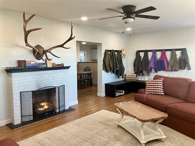 living area with a fireplace, baseboards, wood finished floors, and recessed lighting