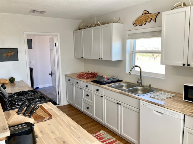 kitchen featuring visible vents, dishwasher, black gas range oven, wood finished floors, and a sink