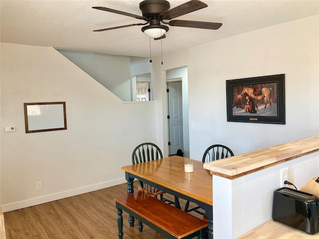 dining room featuring a ceiling fan, baseboards, and wood finished floors