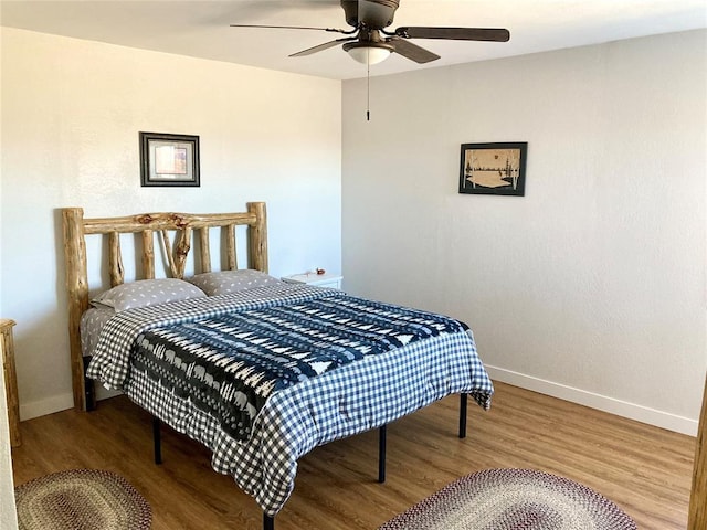 bedroom with ceiling fan, baseboards, and wood finished floors