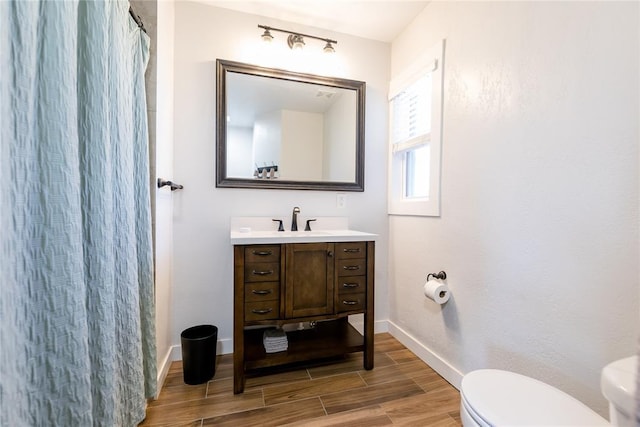 full bath with wood finish floors, curtained shower, toilet, vanity, and baseboards