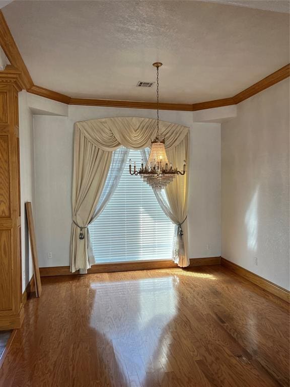 unfurnished dining area featuring ornamental molding, a chandelier, hardwood / wood-style floors, and a textured ceiling