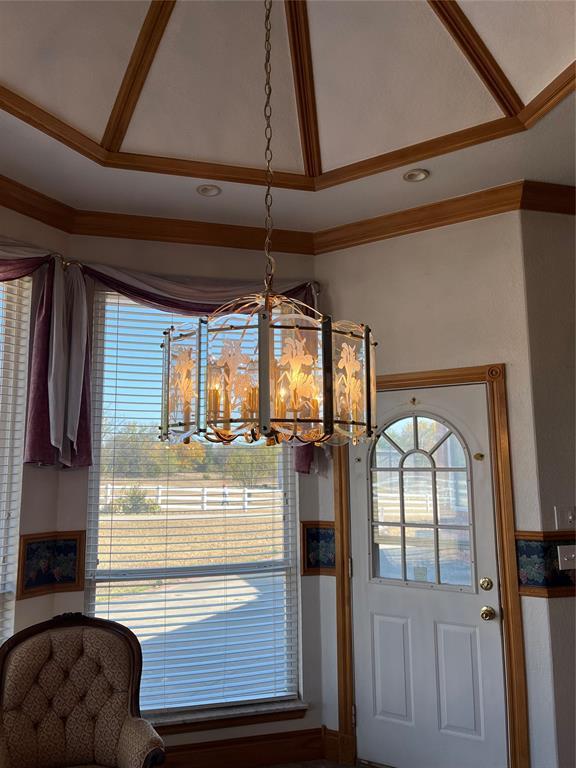 doorway to outside with crown molding, lofted ceiling, and a chandelier