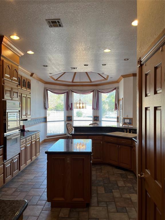 kitchen featuring sink, ornamental molding, a center island, and a textured ceiling