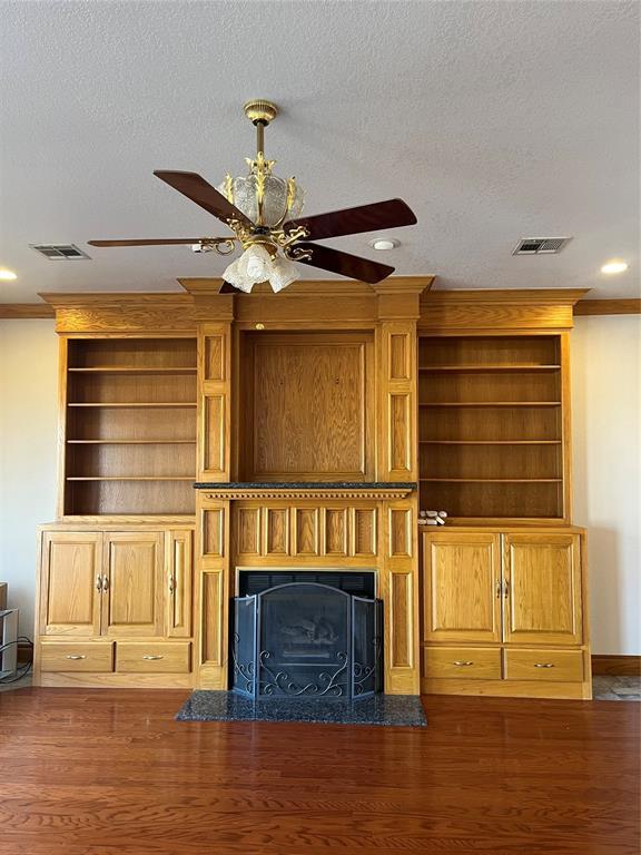 unfurnished living room featuring ornamental molding, dark hardwood / wood-style floors, and a textured ceiling