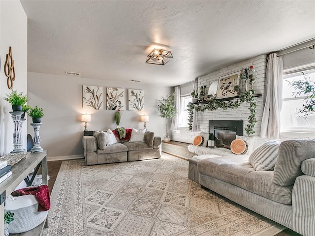 living room with a fireplace, a textured ceiling, and light wood-type flooring