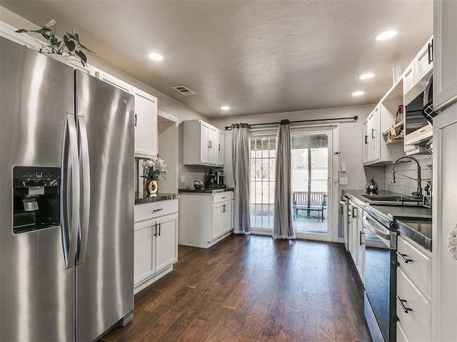 kitchen featuring appliances with stainless steel finishes, tasteful backsplash, white cabinetry, sink, and dark wood-type flooring