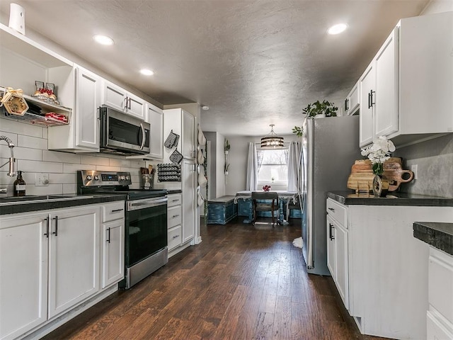 kitchen featuring sink, dark wood-type flooring, appliances with stainless steel finishes, backsplash, and white cabinets