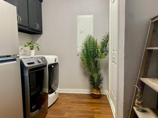 washroom featuring hardwood / wood-style flooring, cabinets, and washing machine and dryer